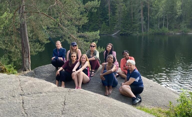 A group of women gathered on rocks beside a lake